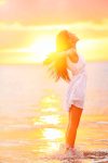 Free woman enjoying freedom feeling happy at beach at sunset. Beautiful serene relaxing woman in pure happiness and elated enjoyment with arms raised outstretched up. Asian Caucasian female model.